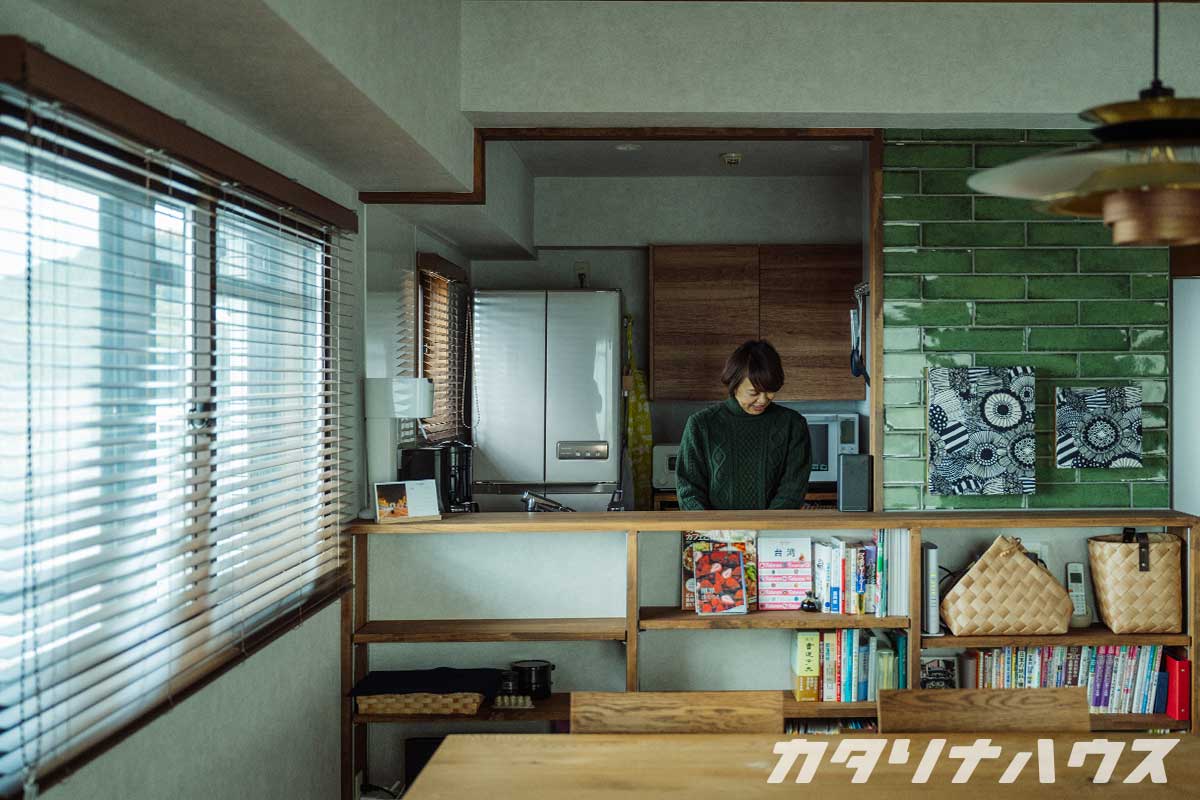 中古マンションのリノベーションを行ったリビング。緑色のクラフトタイルをあしらった造作カウンター越しにキッチンが見える。