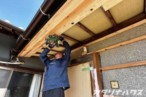 リノベーション中の木造住宅。玄関の軒天に化粧板を施工する大工さん。