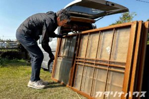 役目を終えた建具からレトロなガラスを取り外し、リノベーションに使用する。慎重にガラスを取り外す男性。