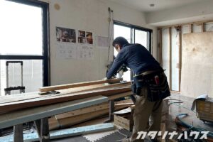中古マンションの室内で、間取り変更のために木材をカットする職人の様子
