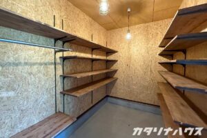 リノベーションでつくられたOSB合板仕上げの収納部屋。壁一面に可動棚とハンガーパイプを設置