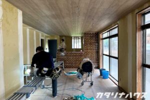 中古住宅のリノベーション現場。クロス貼り前の下地処理と仕上げ作業を行う職人たちの様子