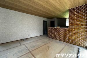 中古住宅のリノベーションで仕上げ直前の室内。タイル張りの腰壁と木目天井が特徴的な空間