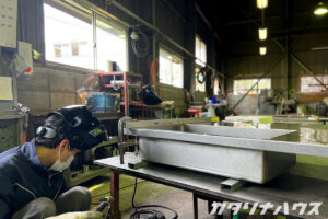 工場内で造作キッチンのシンク部品を固定している作業工程