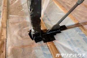 床下の気密シートと柱のすき間を丁寧に気密テープで塞ぐ施工の様子