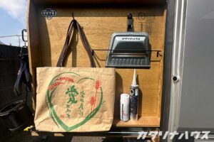 荷室カスタムの収納棚に小物を収納。フックに袋をかけ、掃除用具やシーリング材を整理して配置。