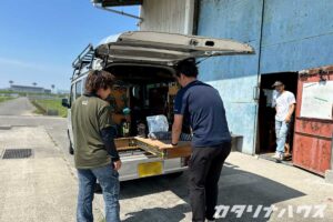 木工職人に軽バンのカスタムを披露する男性スタッフ。