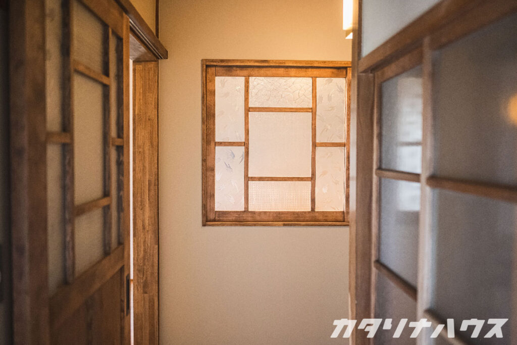 廊下から見たレトロな模様ガラスの室内窓と引き戸。木枠の温かみと和モダンな雰囲気が漂う。