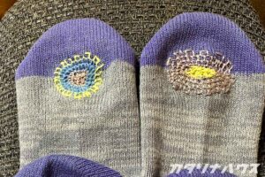 つま先にカラフルな糸で丸くダーニング刺繍が施された靴下。左右で異なる配色。