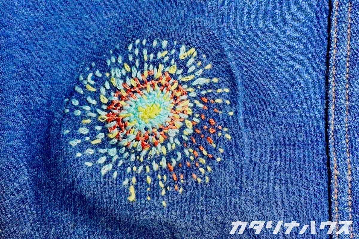 ひざ部分に花火のような刺繍が施された子ども用デニム風レギンス。補修後の完成形。