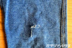 デニムのひざ部分のアップ。穴があいて白い糸が出ている状態。