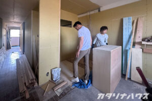マンションリノベーション工事中の室内。壁下地が施工されたスペースに、職人さんがヌックの位置を確認している様子。