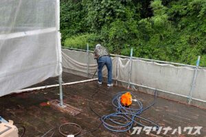 高圧洗浄で屋根の古い塗膜や汚れを丁寧に除去する作業中の様子。
