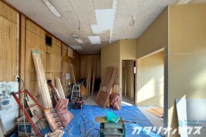 壁下地と石膏ボードが取り付けられ、ブルーシートが敷かれた室内の施工中の様子