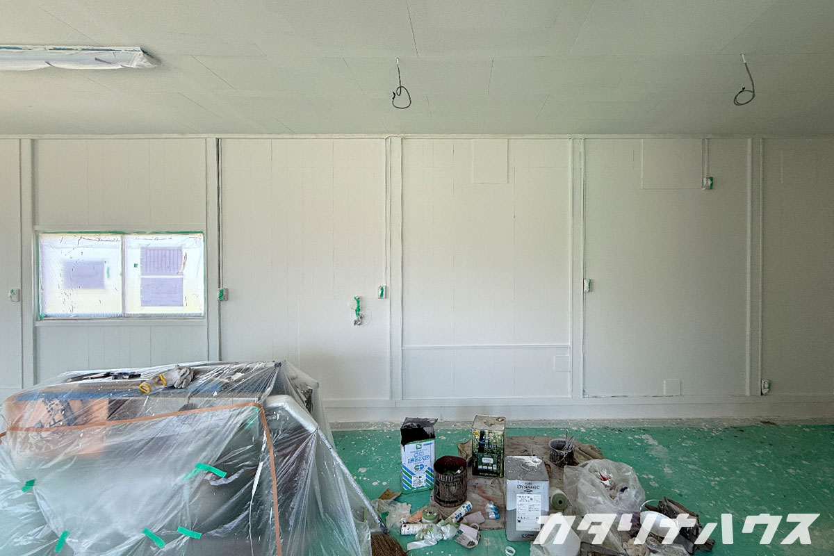 白く仕上がった内壁と、塗装作業の道具や資材が置かれた室内の様子