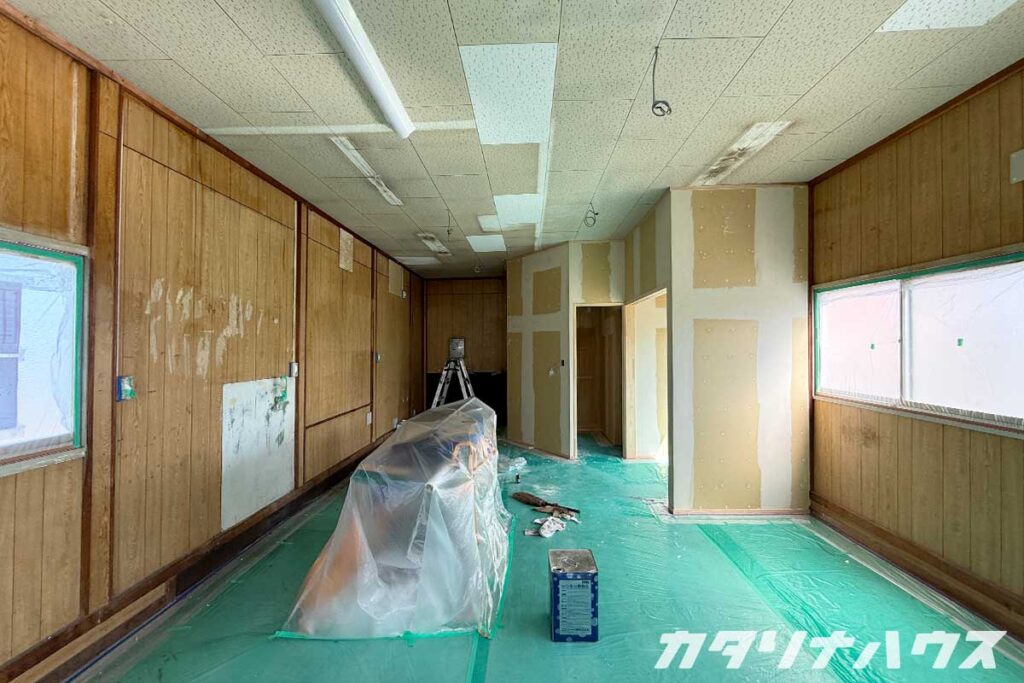 壁の一部にパテ処理が施され、照明器具や道具が置かれた下地処理中の店内の様子