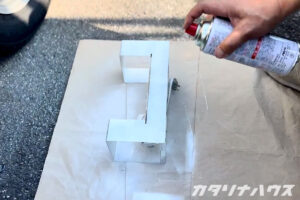 金属製の照明器具を白いスプレーで塗装している手元のアップ