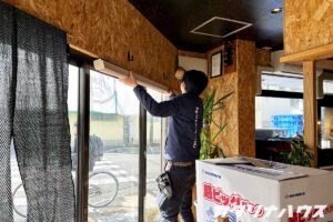 掃き出し窓の前でロールカーテンを設置する男性スタッフ