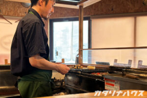 店内で焼き鳥を調理する男性。
