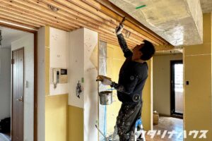 職人が天井の木部に塗装を施している様子