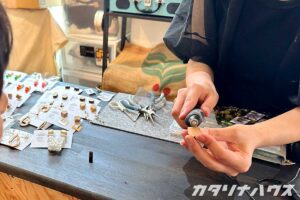 愛媛県産材で作られた耳飾りのワークショップ。木を電動やすりで削る女性の手。