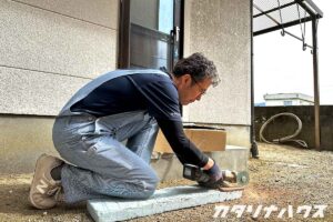 屋外で電動工具を使いタイルをカットするスタッフ。現場に合わせたサイズ調整を行うタイル施工の様子