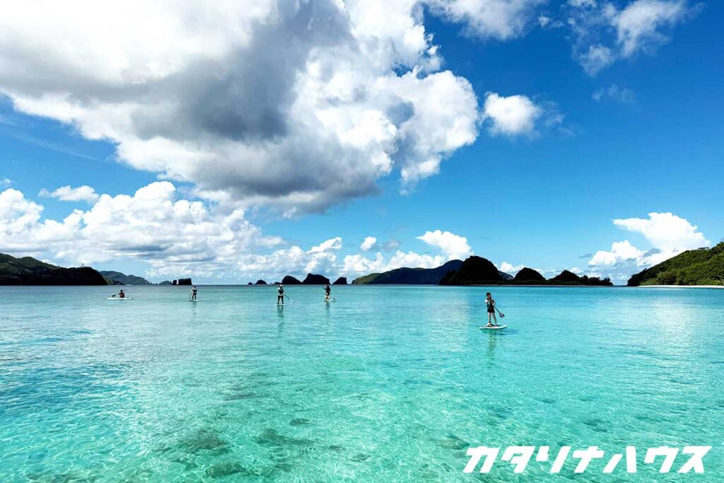 真っ青な海に浮かぶSUPボード。背景には島々が広がり、南国らしい風景が広がる