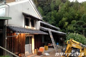 １階部分は焼杉が貼られ２階部分は漆喰で仕上げられた蔵造りの古民家。屋根は落ち、工事の為梯子がかけられている。