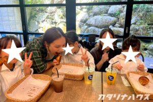 石垣が見えるロケーションの教室でパンを食べる母と子のグループ。テーブルにはアイスドリンクとクロワッサン。