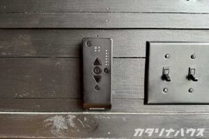 壁につけられたブラインドのリモコン。黒く塗った板張りの壁。