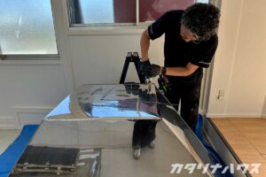 男性職人が工具を使ってステンレスのレンジフードに穴をあけている。