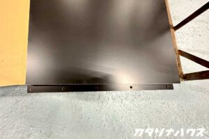 ダボを入れる用の穴が複数空いた黒いキッチンのサイドパネル。