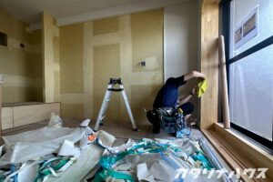 石膏ボードにクロスを貼る職人の姿。