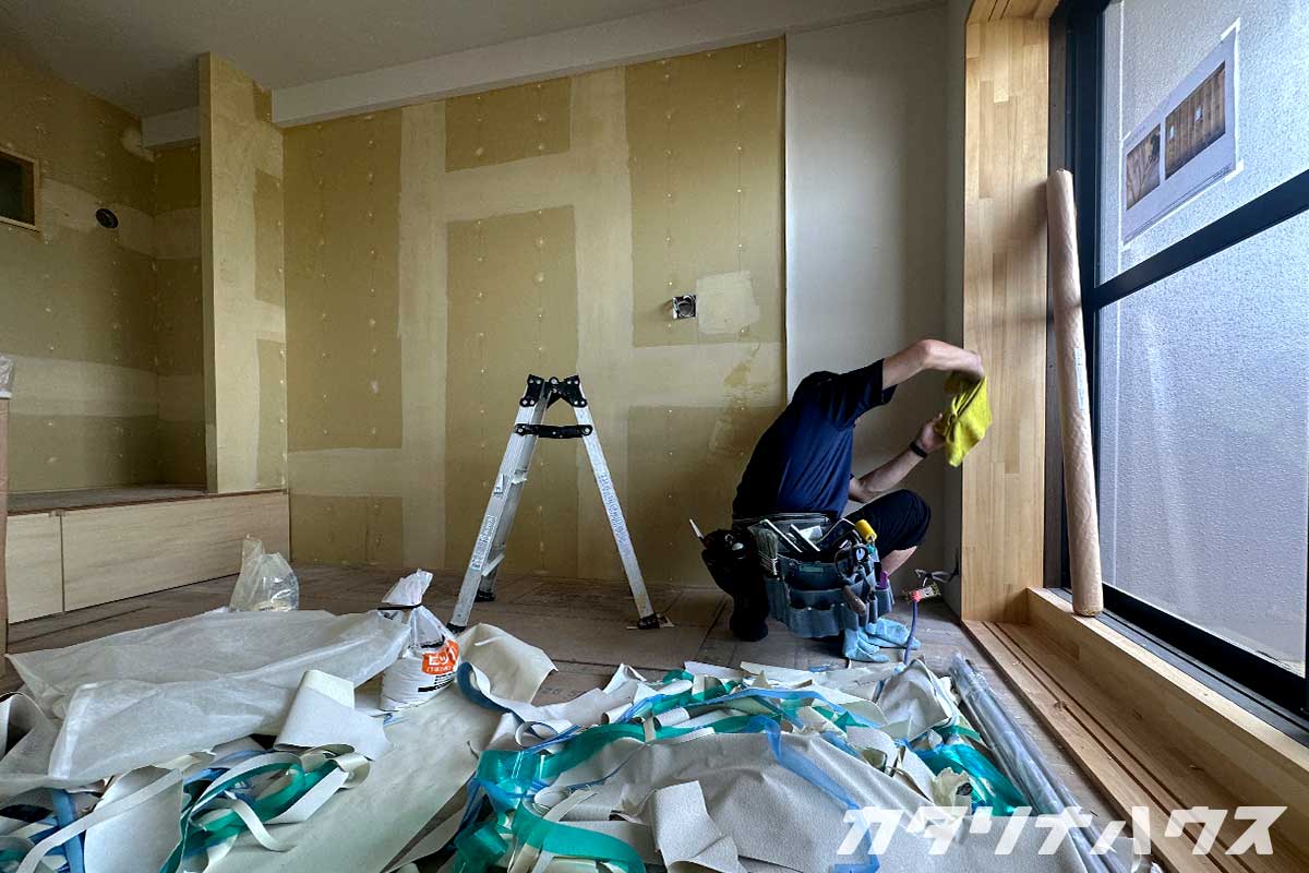 石膏ボードにクロスを貼る職人の姿。