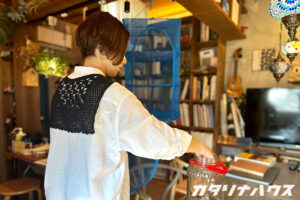 吊るされた干しかごから梅干をビンに移すスタッフ