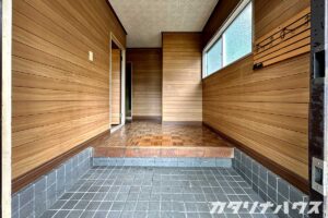 リノベーション前の中古住宅の玄関ホール。木目の壁材とモザイク調の床タイルが特徴的な昭和レトロな内装