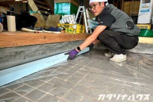玄関土間に断熱材を敷き詰めるため、スタイロフォームをサイズ調整しながら設置する職人の作業風景。中古住宅の断熱リノベーション