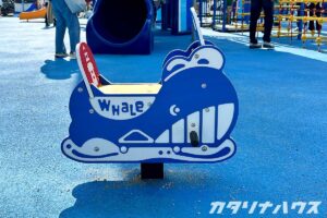 青いくじらをモチーフにしたスプリング遊具が設置された公園の一角。子どもが乗って揺らして遊べるデザインで、海のテーマに合わせた遊具エリアの様子。