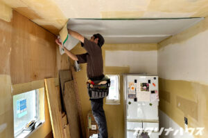 天井にクロスを貼る職人の姿