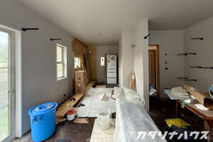 壁紙を貼り終わった壁にキャットウォーク用の黒い棚受けを取り付けている