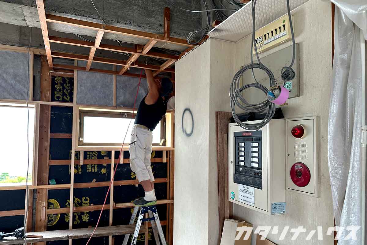 脚立に上りリノベーション工事を行う職人さん。