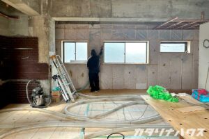 リノベーション中の室内で、壁の中に断熱材を吹き込む職人。