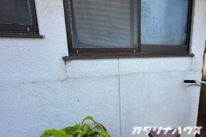 築30年ほどの木造住宅の白い外壁にクラックが入っている。