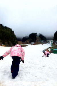 人口雪で作られたスキー場を歩く子供