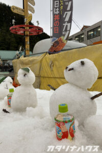 小さな雪だるまに並んでリンゴジュースが冷やされているスキー場の光景