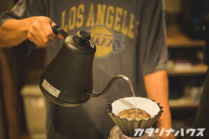 黒いケトルを使ってコーヒーをペーパードリップする男性