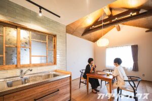 梁が見える古民家リノベ。タイルがあしらわれたキッチンにはレトロガラスの室内窓がある