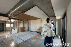 リノベーション工事中の室内で、解体後のLDK空間を確認しながら打ち合わせをしている様子
