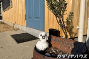 陶器の看板に小さいゆきだるまが寄り添う