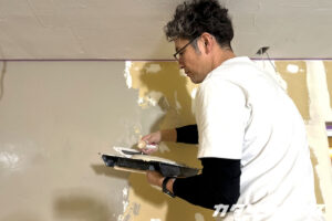 スモーキーグリーンの漆喰を塗る男性